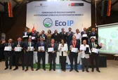Grupo de funcionarios en dos filas sosteniendo certificados de reconocimiento como 'Modelo EcoIP'. La imagen captura el momento de la distinción otorgada por el Ministerio del Ambiente (MINAM) al Fondo MIVIVIENDA por su gestión de prácticas ecoeficientes
